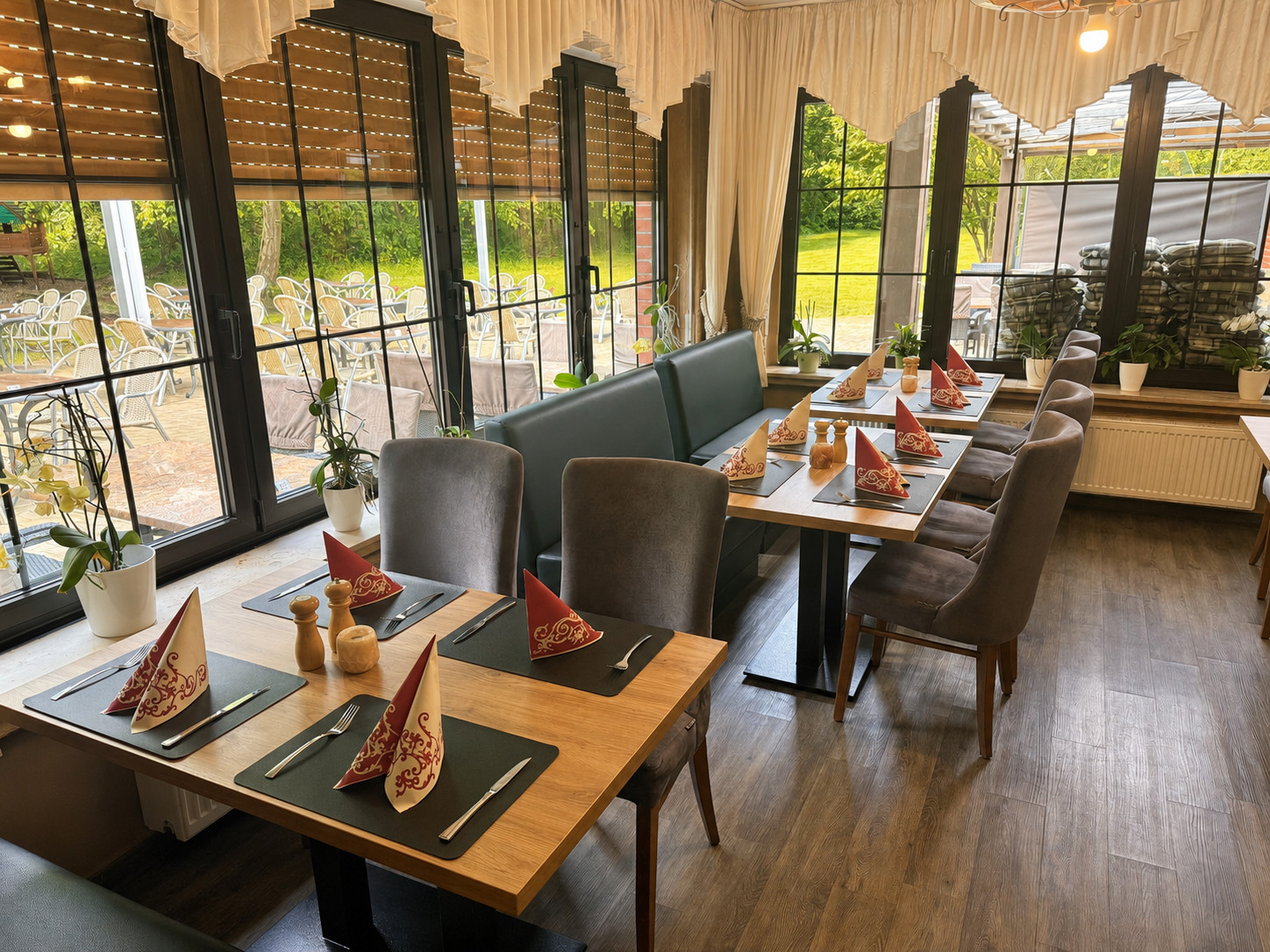 Gedeckte Tische im hellen Gastraum vom Restaurant Im Grünen Winkel mit Blick auf Terrasse und Garten